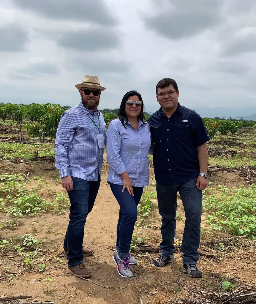 three people standing on farm smiling